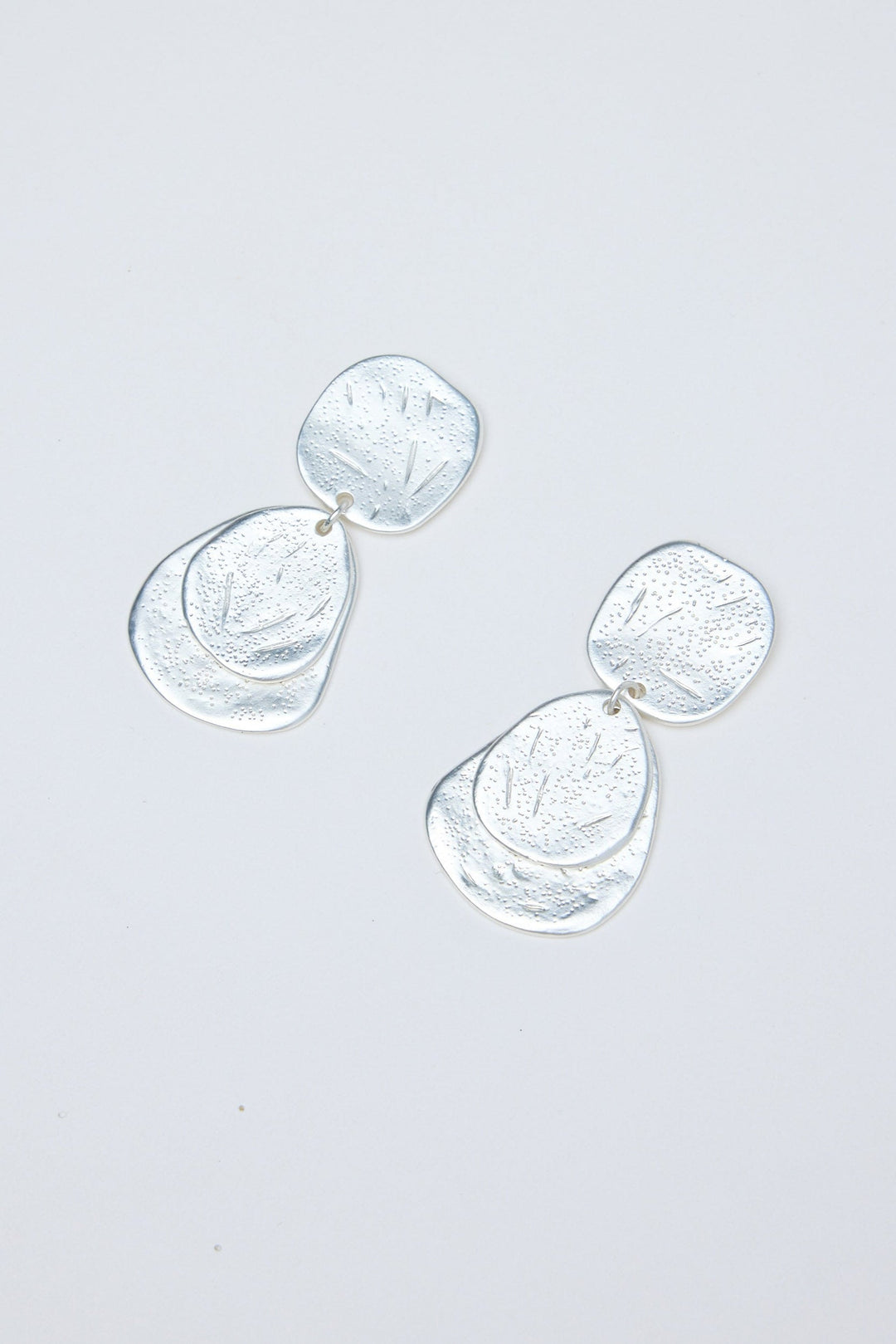 Silver earrings on a light gray background