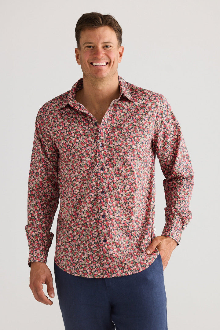 Man wearing a red floral shirt and navy shorts on a white background