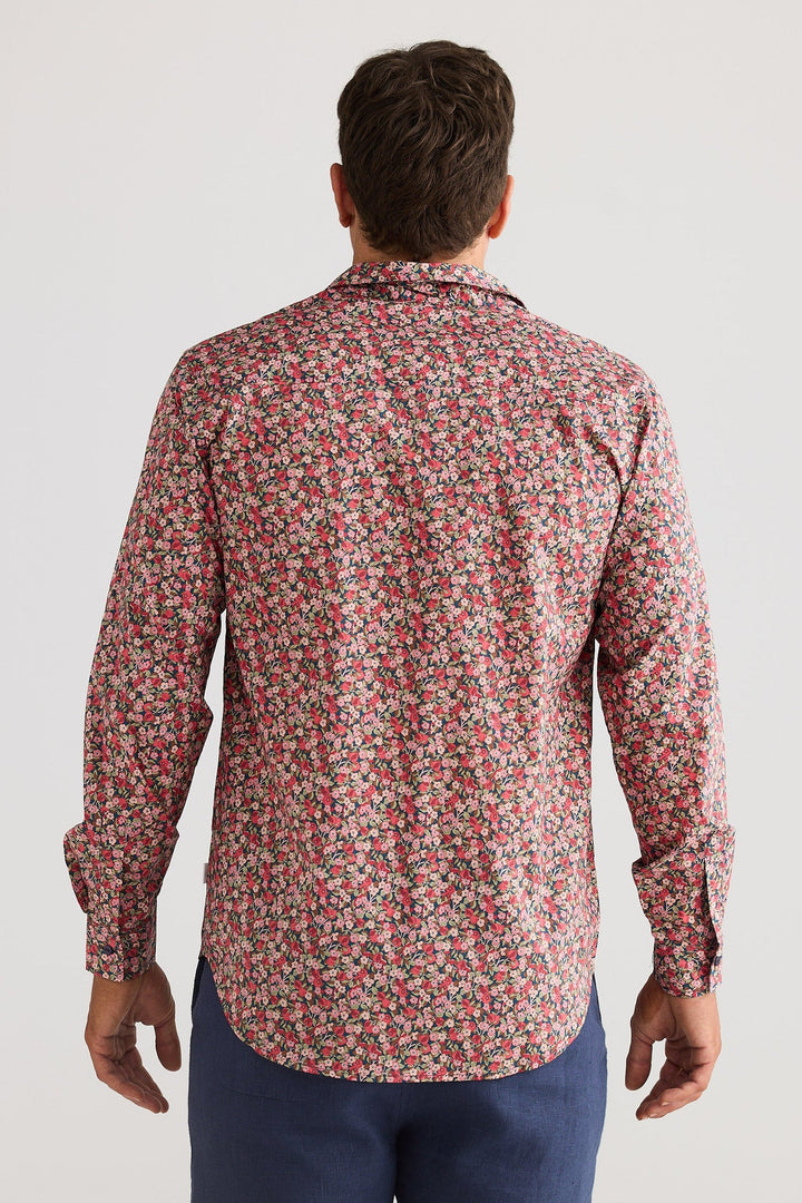 Man wearing a patterned shirt and navy shorts on a white background