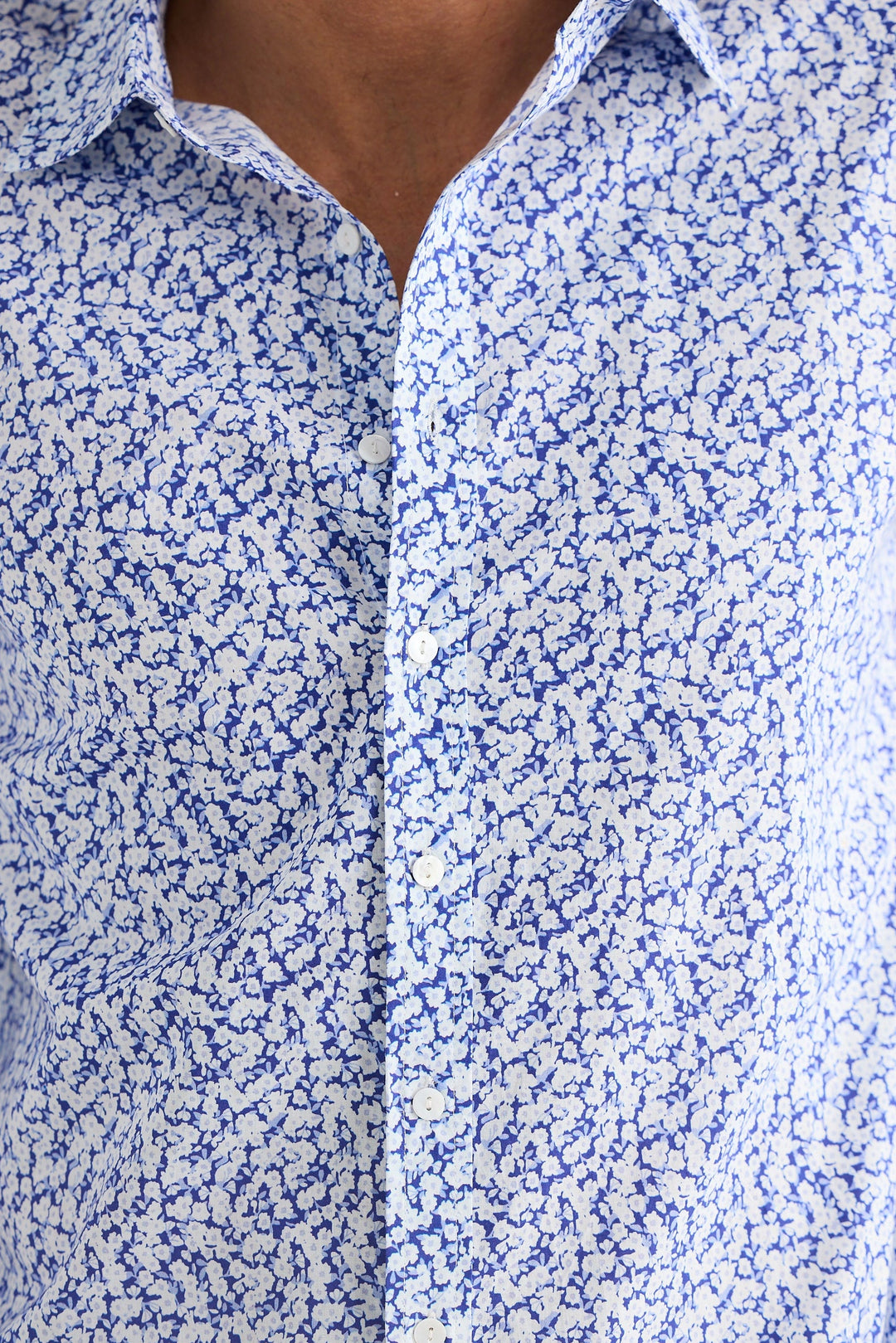 Close-up of a person wearing a blue and white floral shirt.