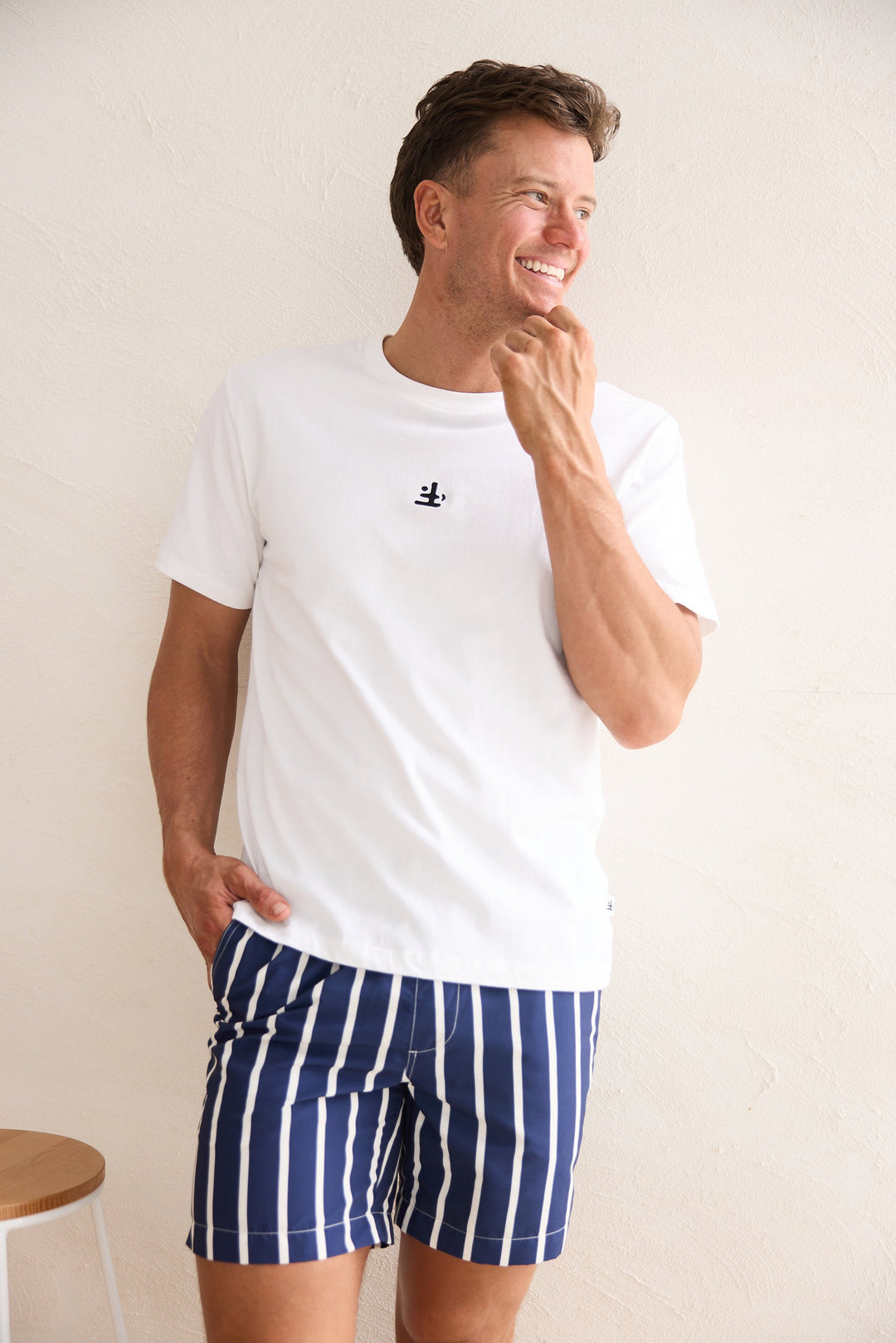 Man wearing a white t-shirt and blue striped shorts against a plain background