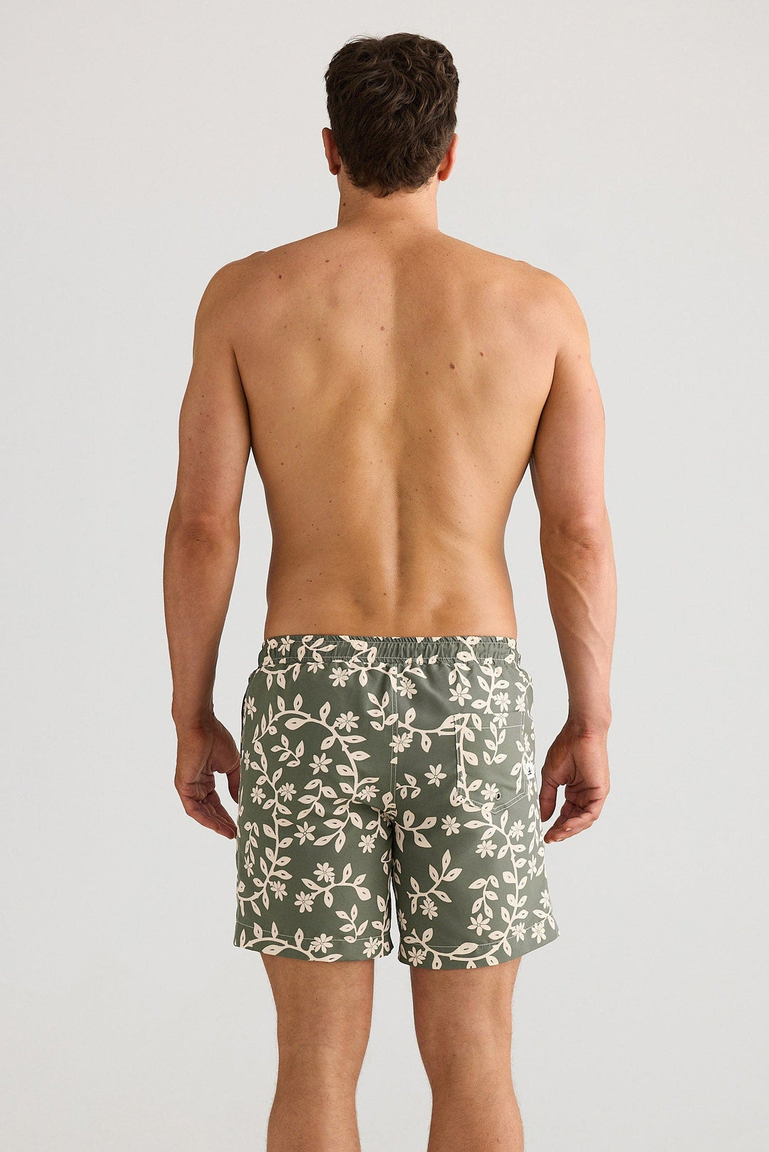 Man wearing green camouflage swim shorts on a white background