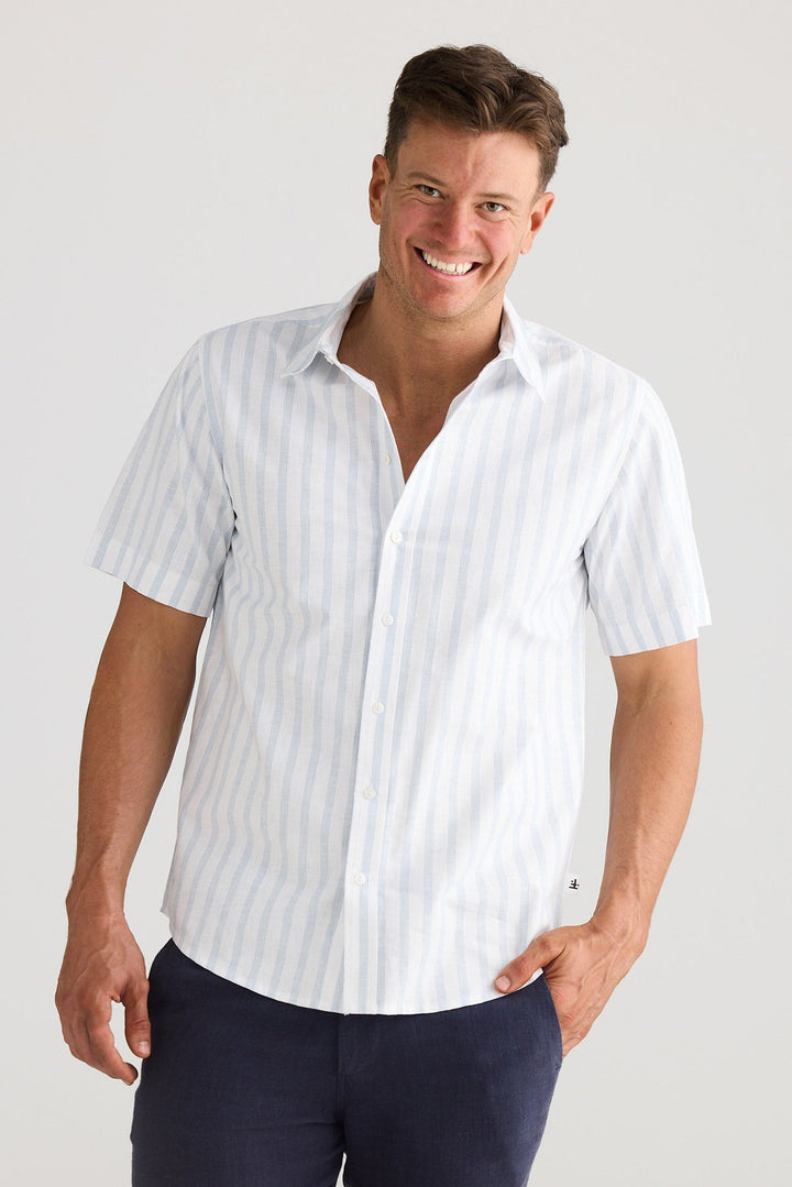 Man wearing a white striped shirt and navy shorts on a plain background