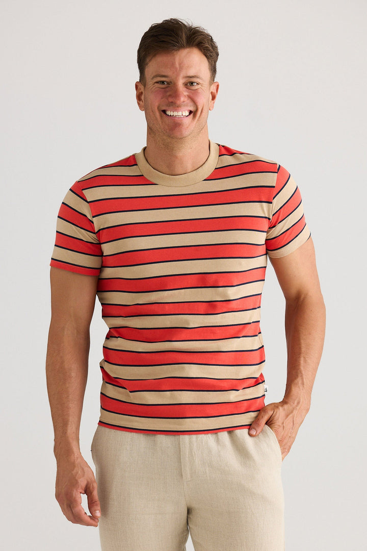 Man wearing a red and beige striped shirt with beige pants on a white background