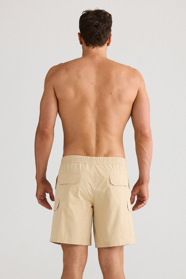 Man wearing beige shorts on a plain background