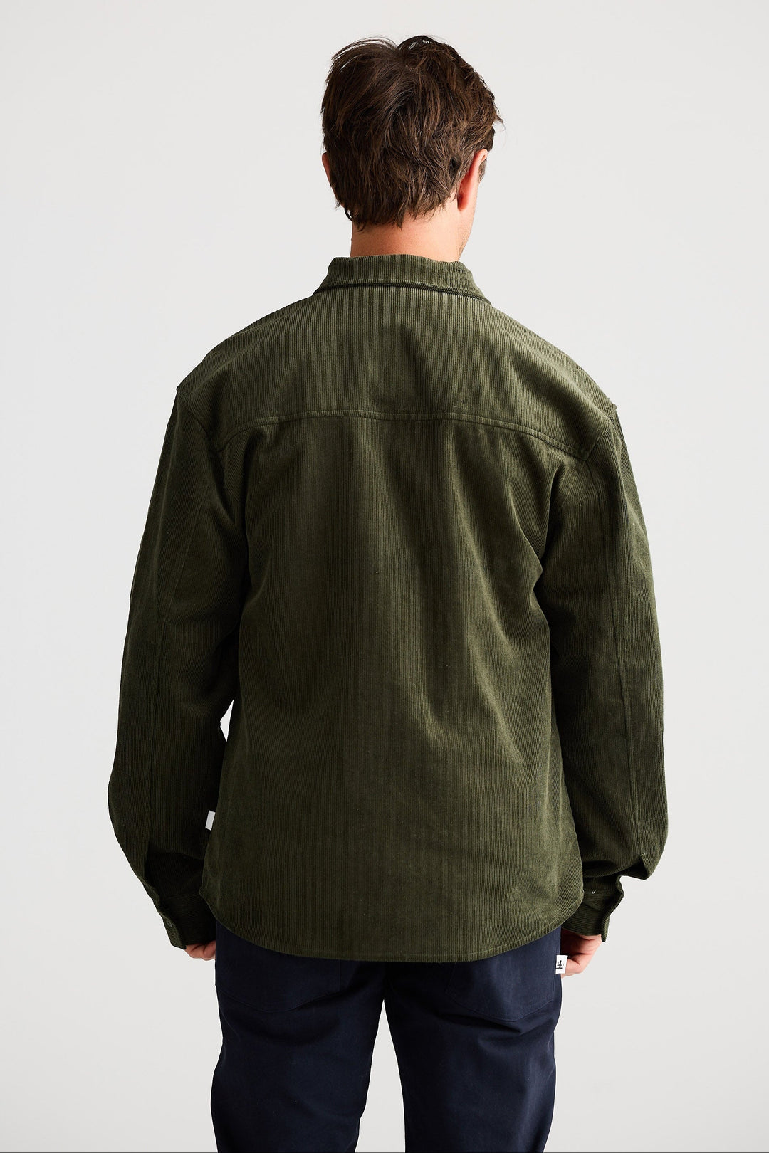 Person wearing a green jacket and dark pants on a white background