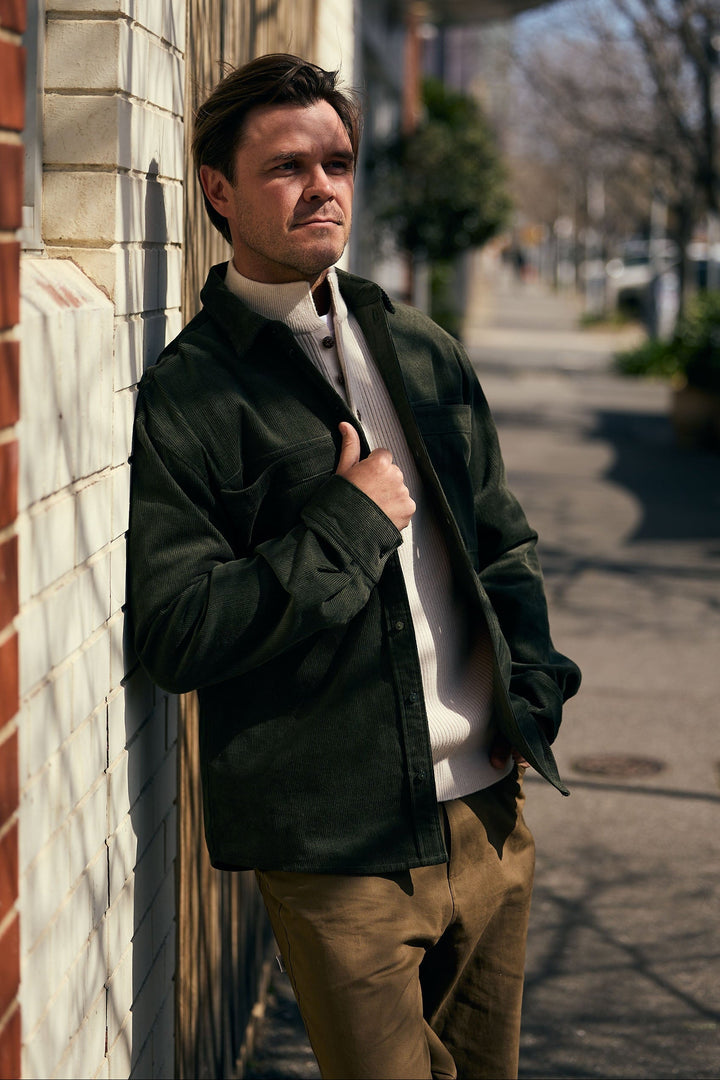Man leaning against a wall on a sidewalk