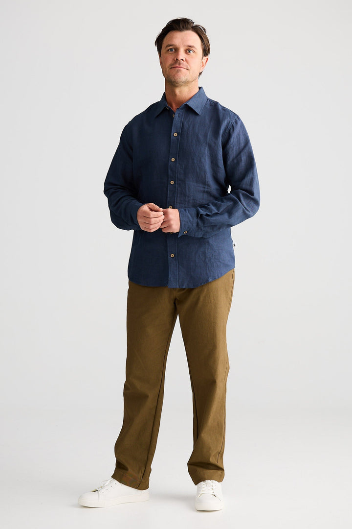 Man wearing a blue shirt and brown pants on a white background