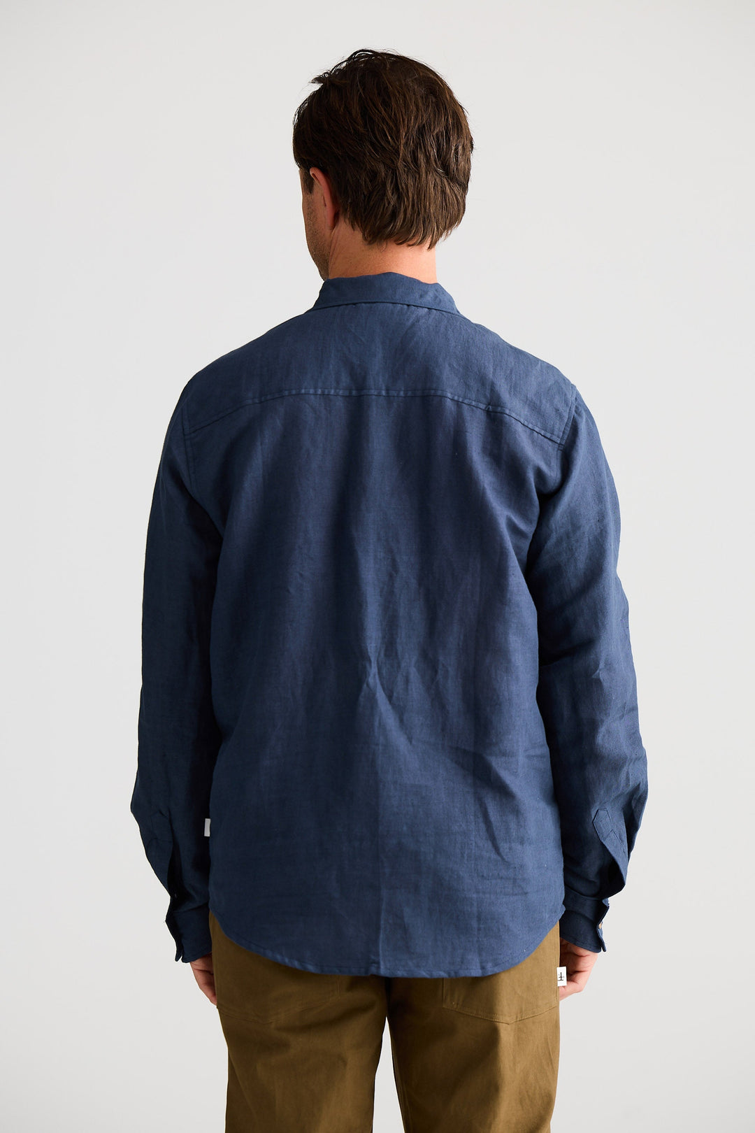Person wearing a blue shirt and brown pants against a white background