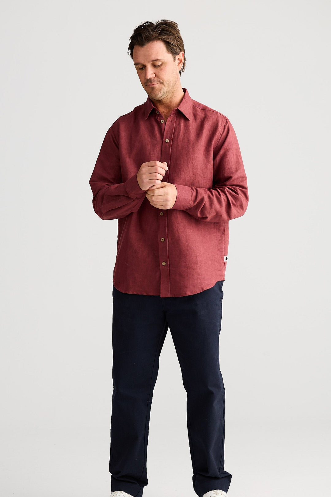 Man wearing a red shirt and dark pants on a white background