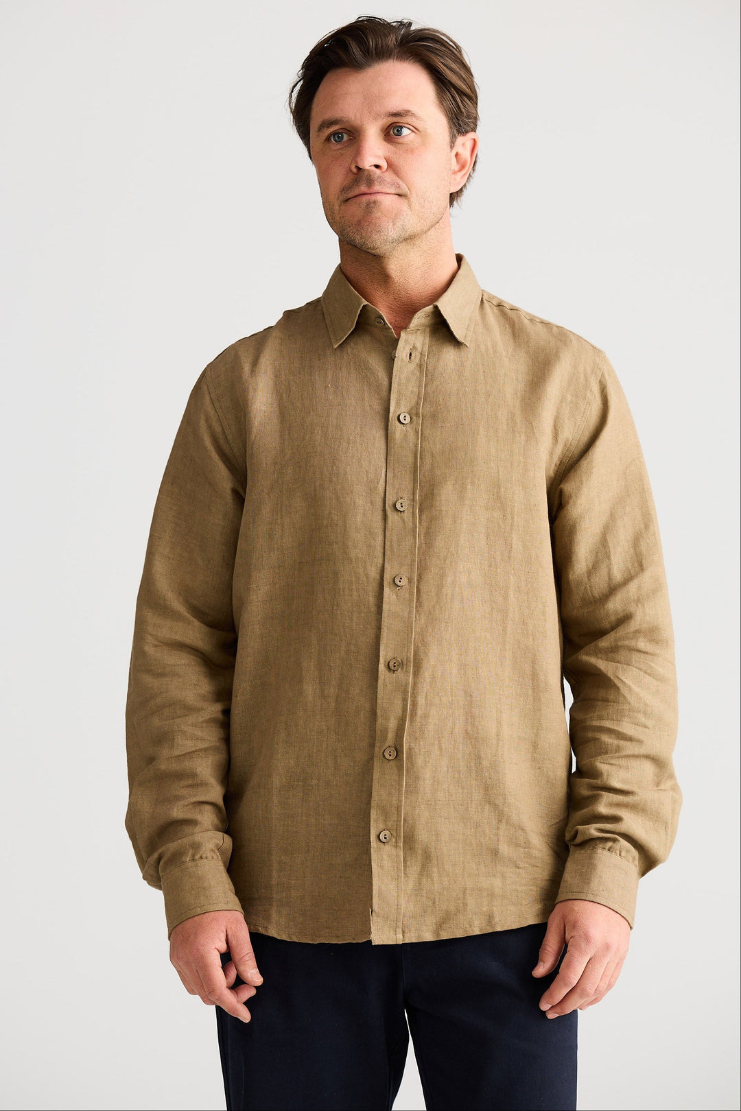 Man wearing a beige button-up shirt against a plain background