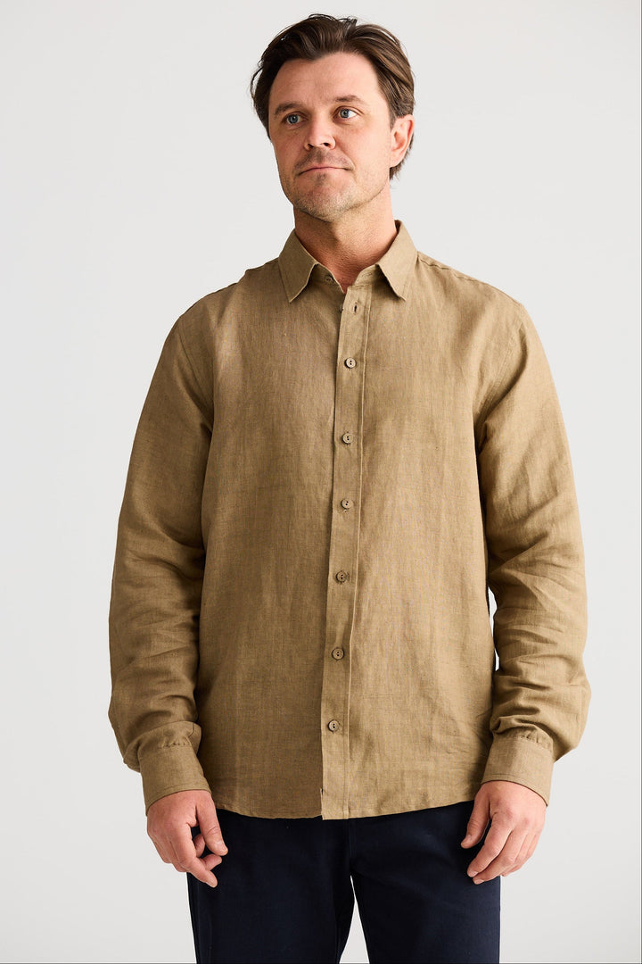 Man wearing a beige button-up shirt against a plain background