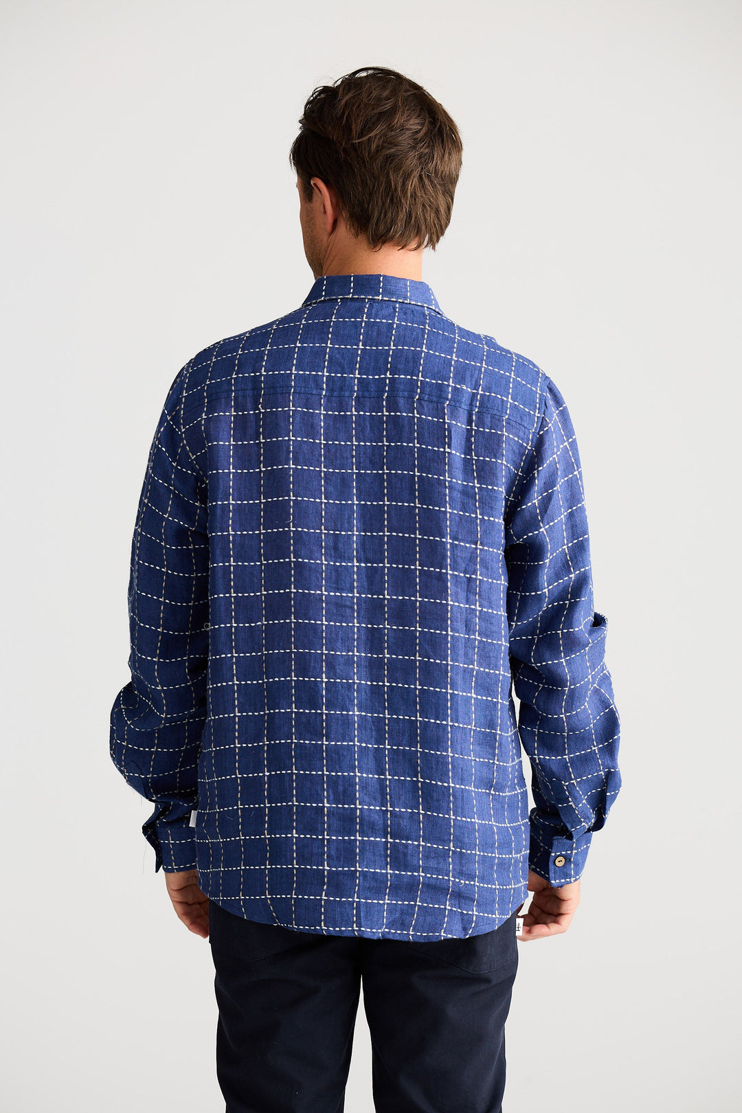 Man wearing a blue checkered shirt against a white background