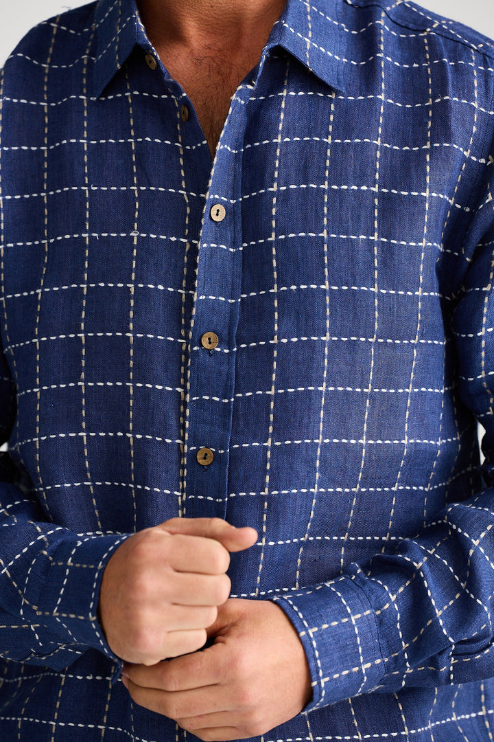 Close-up of a person wearing a blue checkered shirt with a focus on the collar and buttons.