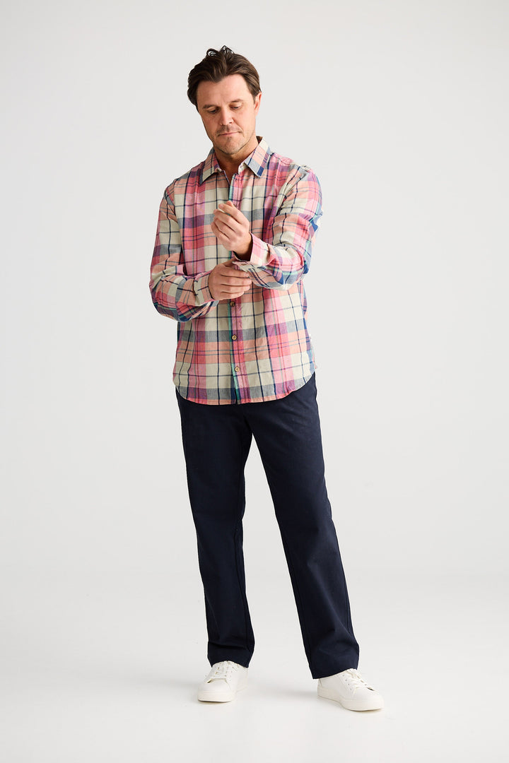 Man wearing a plaid shirt and dark pants on a white background