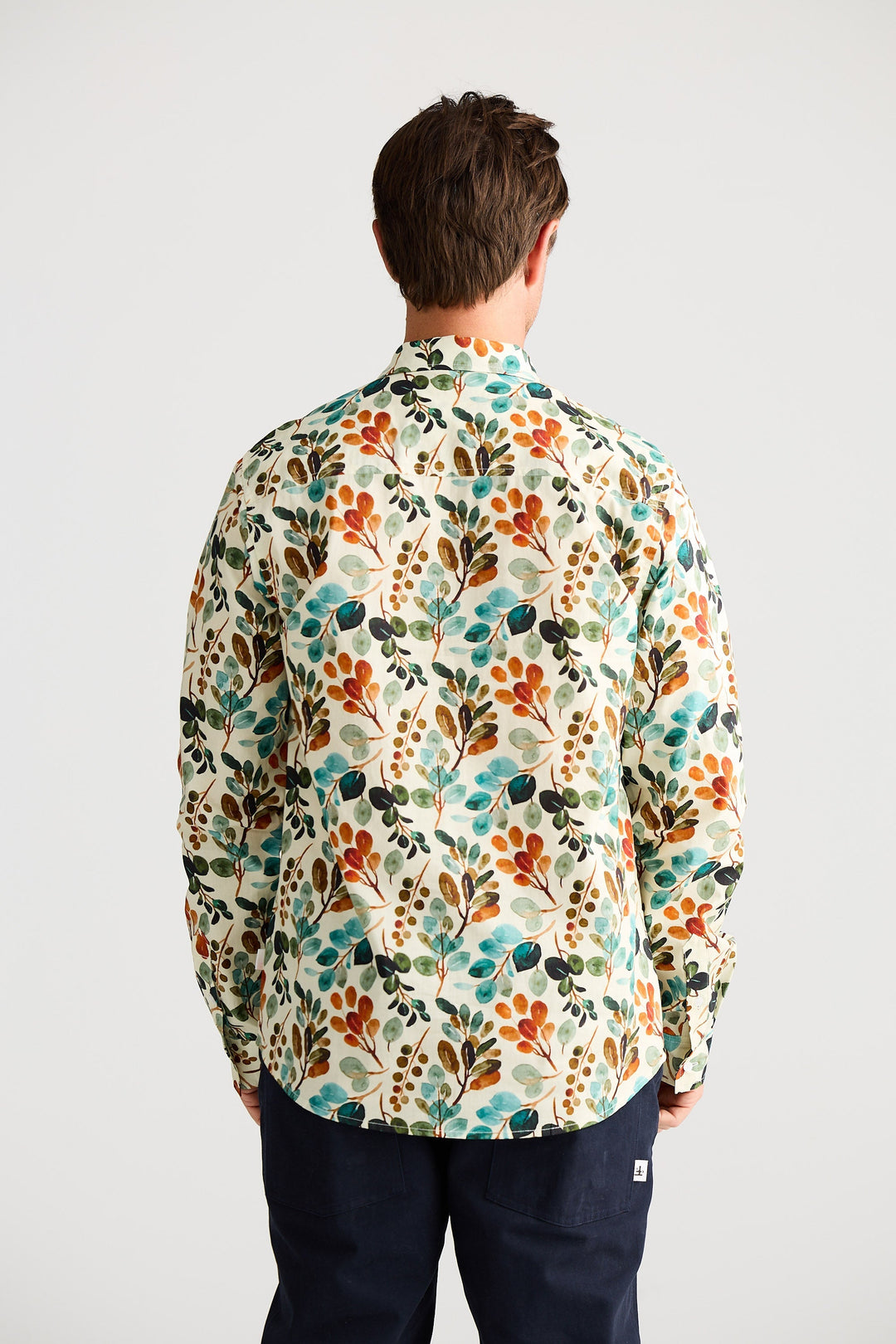 Man wearing a colorful floral patterned shirt on a plain background