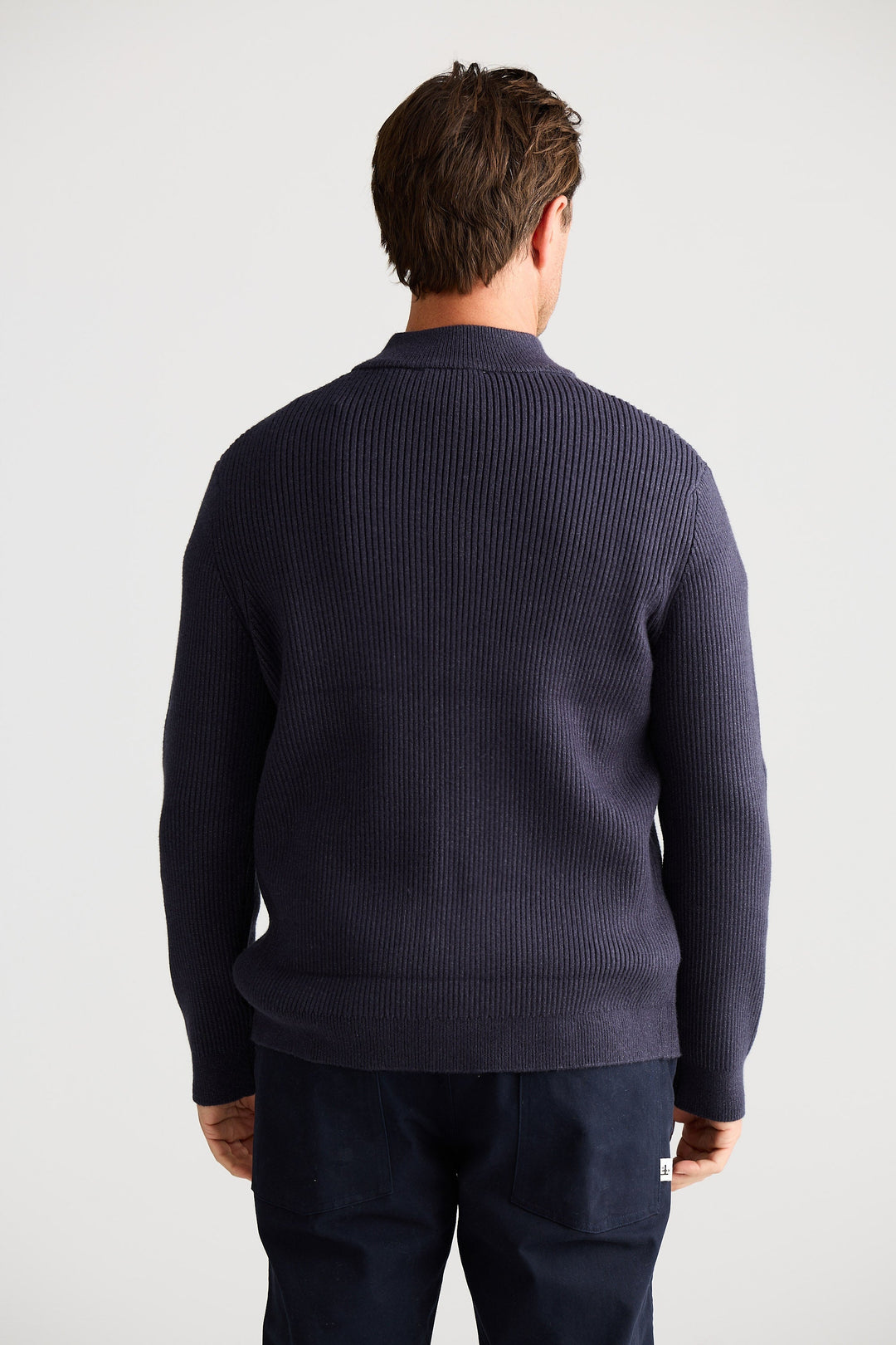 Man wearing a navy blue sweater and pants on a white background