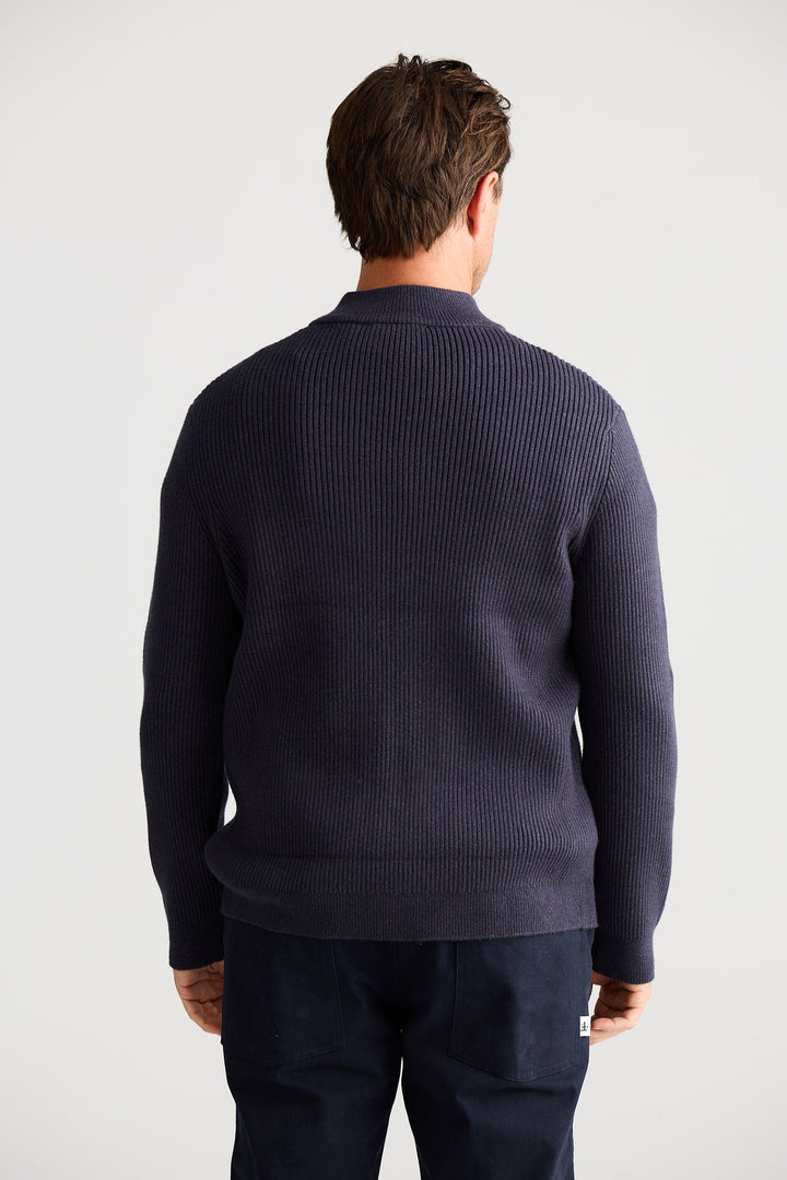 Man wearing a navy blue sweater and pants on a white background