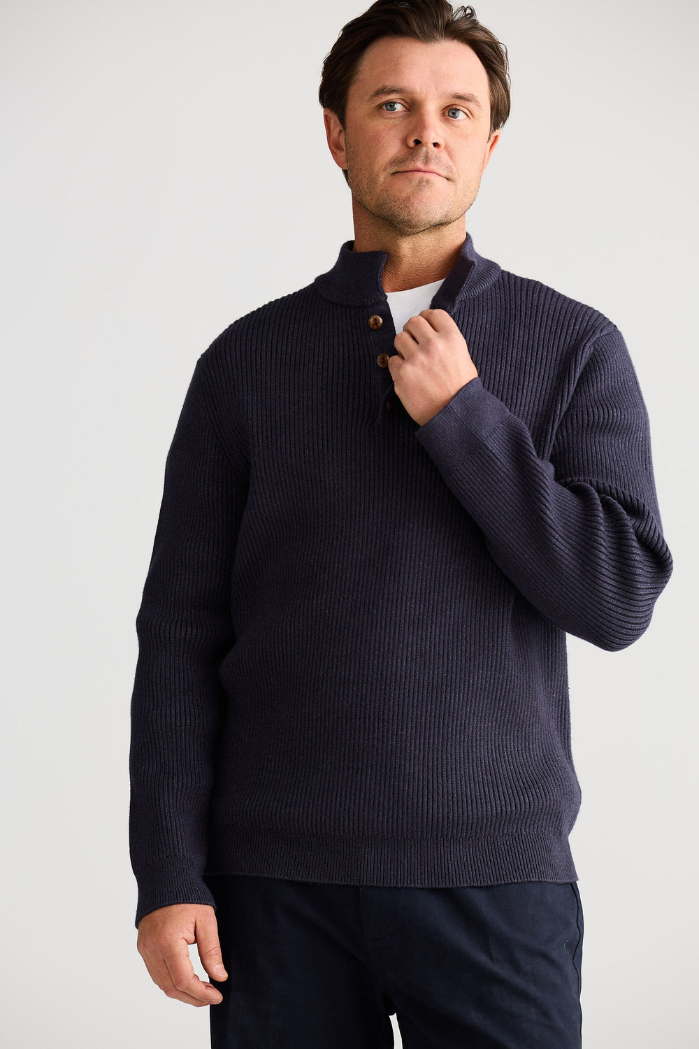 Man wearing a navy blue sweater against a plain background