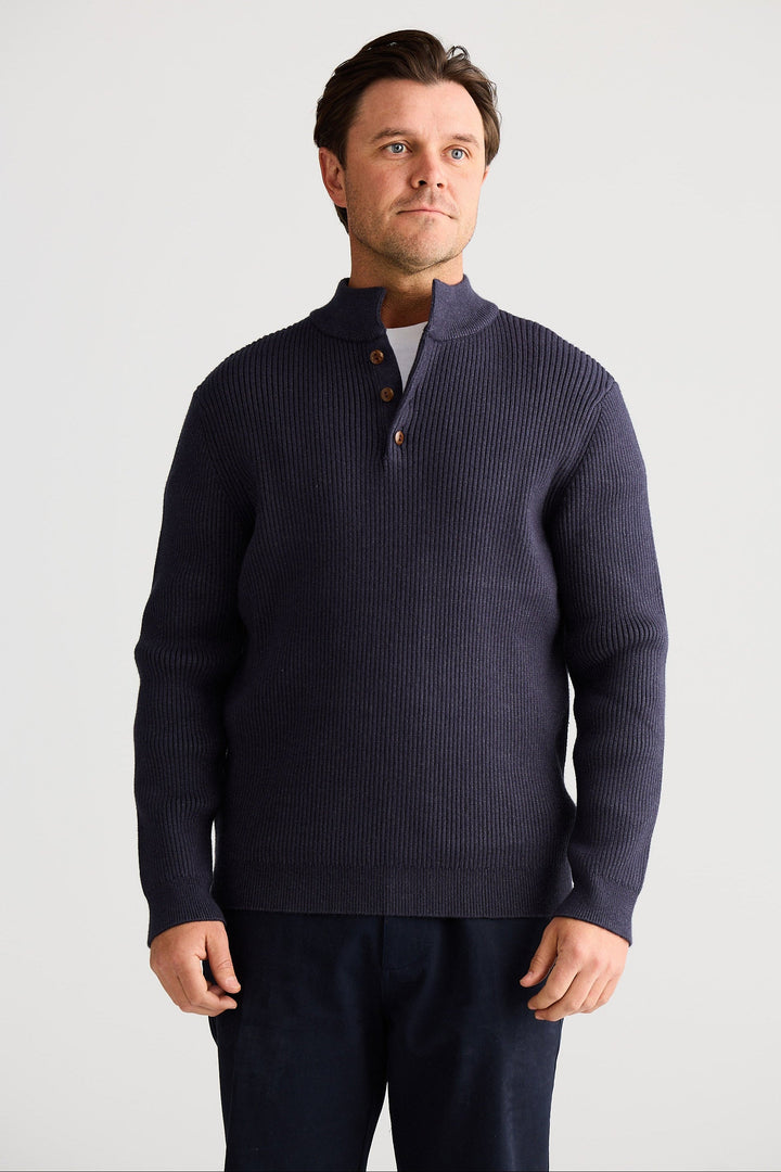 Man wearing a navy blue sweater with a white background