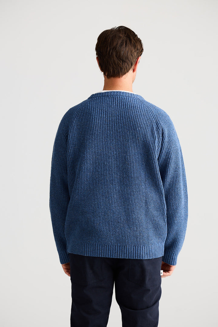 Person wearing a blue sweater from behind on a light gray background