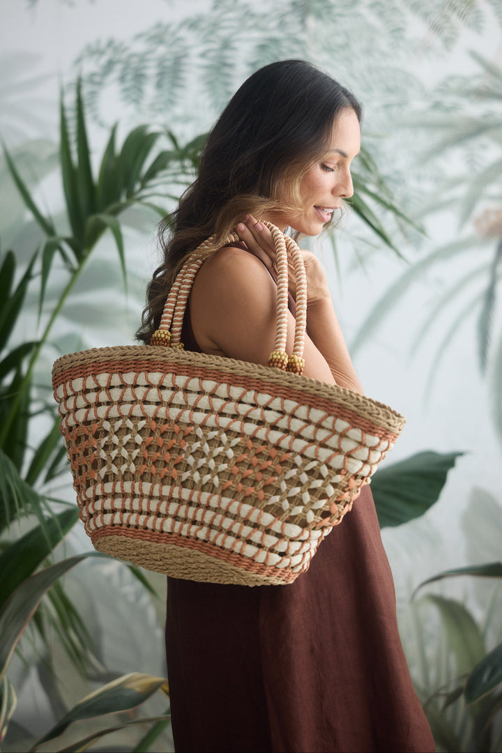 Woman holding a woven basket against a leafy green background
