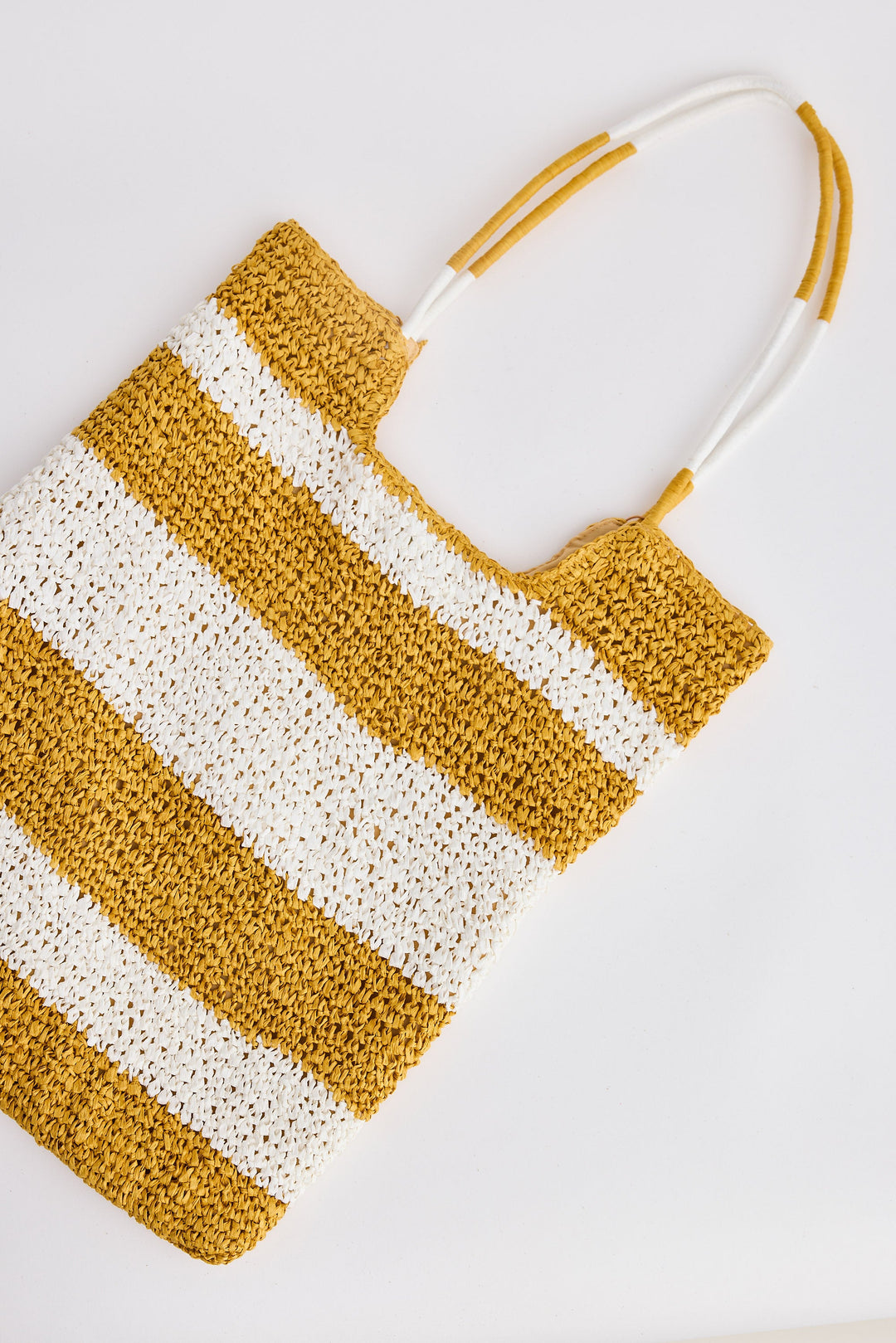 Woven bag with yellow and white stripes on a light gray background