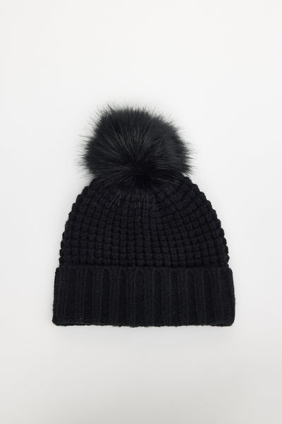 Black knit beanie with a pom-pom on a white background