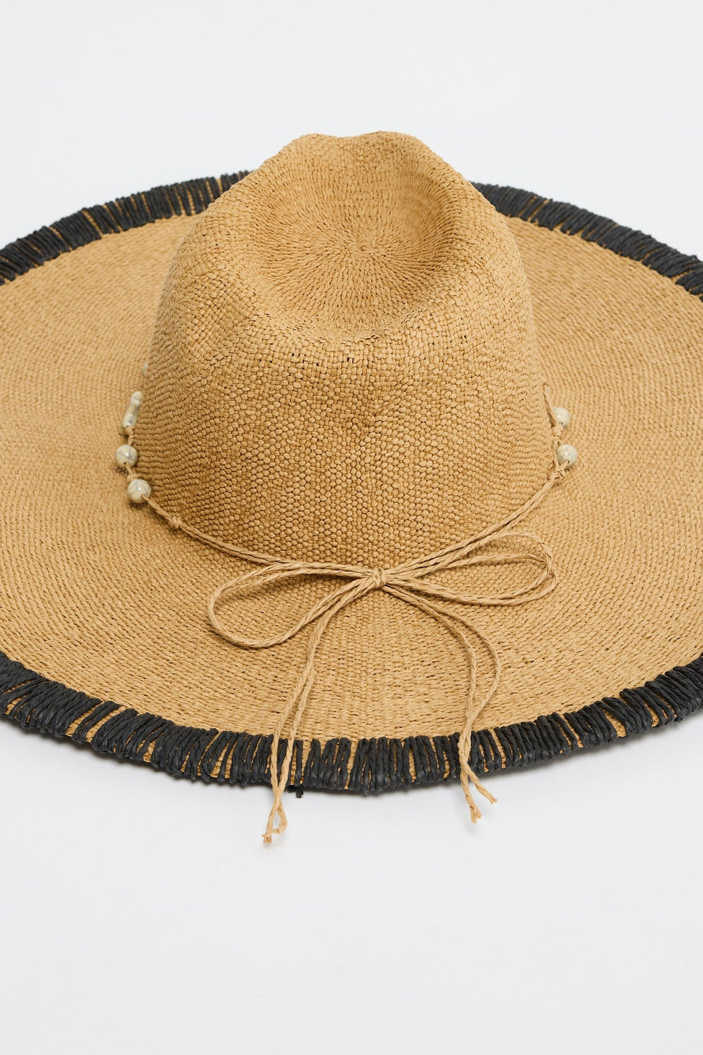 Close-up of the Carlitta Hat's woven texture, black fringed brim trim and beaded raffia tie
