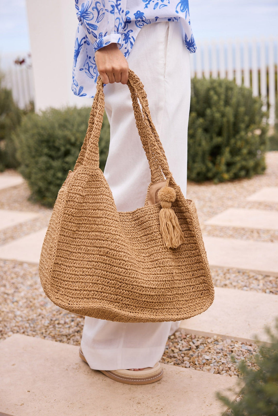 Nora Bag in natural tan worn over the shoulder outdoors, styled with a printed shirt