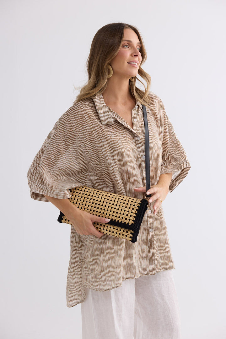 Reema Bag in black worn crossbody, front view held in hand
