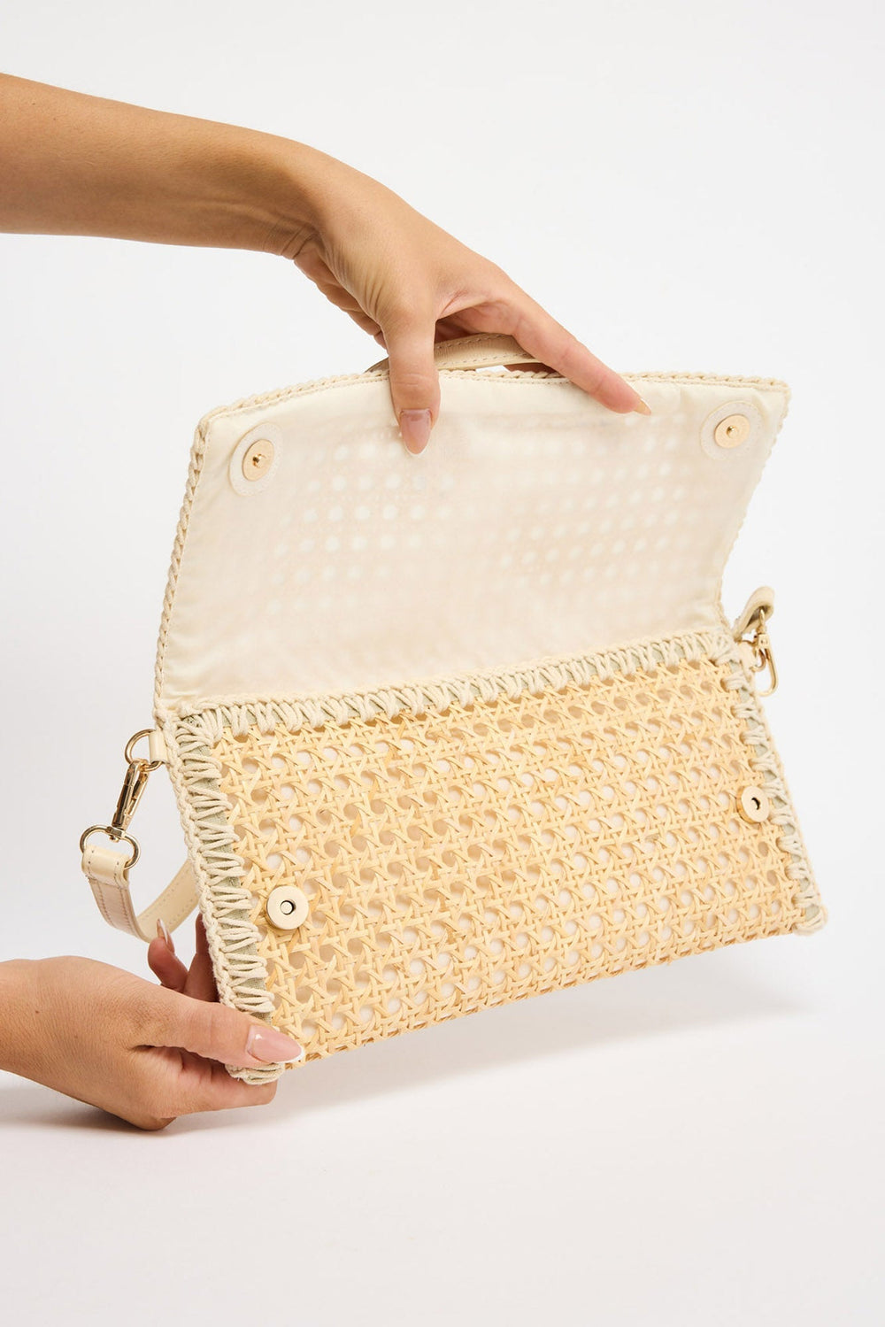 Reema Bag in off white - flap opened by hand, showing the rattan weave and magnetic snap closures