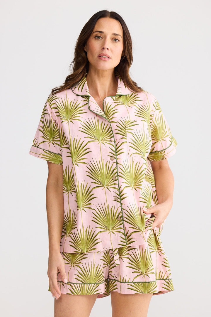 Woman wearing a pink and green palm leaf patterned outfit on a white background