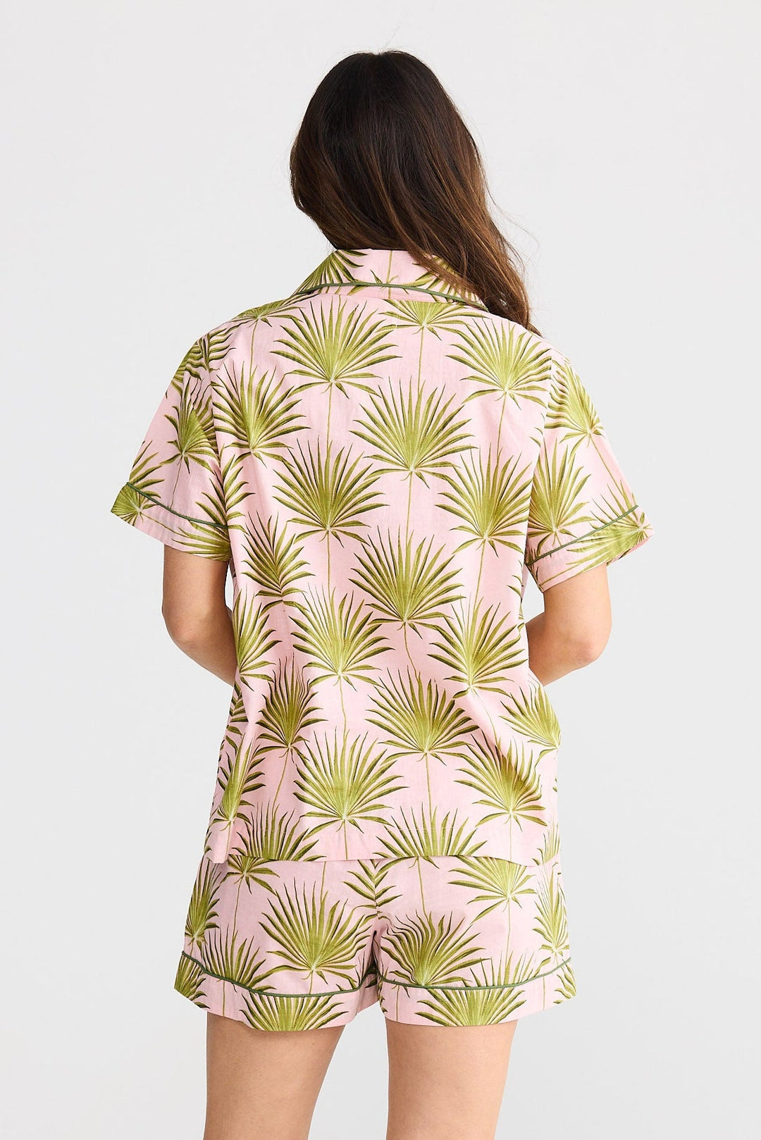 Woman wearing a palm leaf patterned shirt and shorts set on a white background