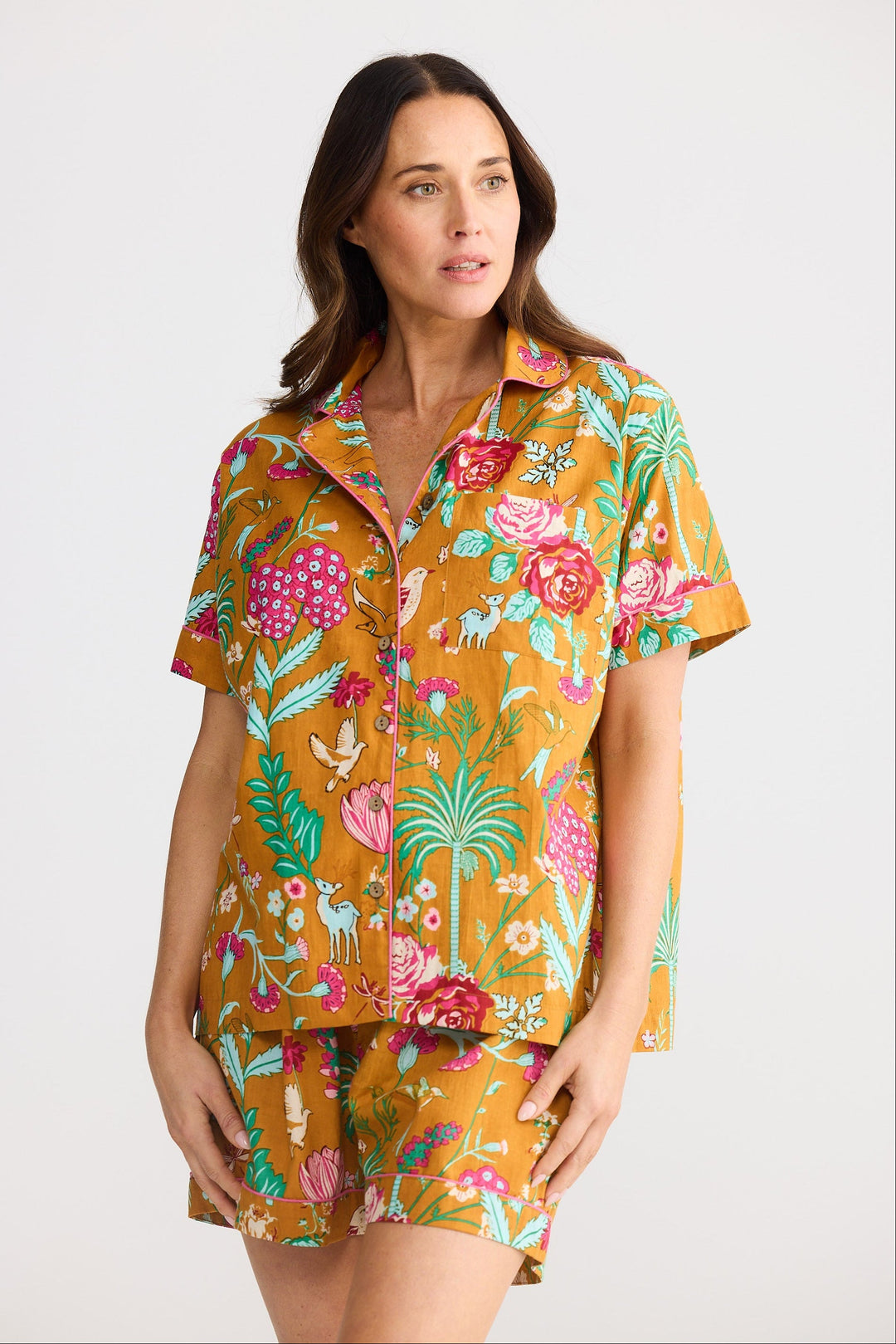 Woman wearing a colorful floral shirt and shorts set on a white background