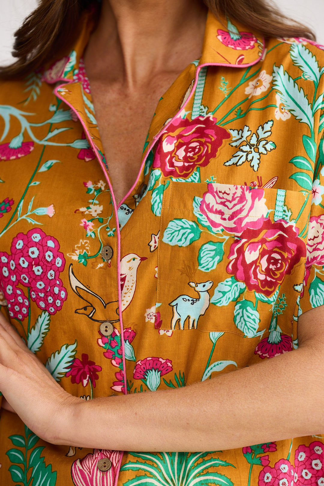 Close-up of a person wearing a colorful floral patterned shirt with mustard yellow background.