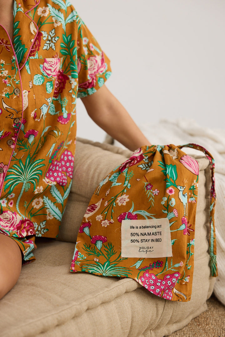 Person wearing a floral outfit with a matching bag on a beige couch.