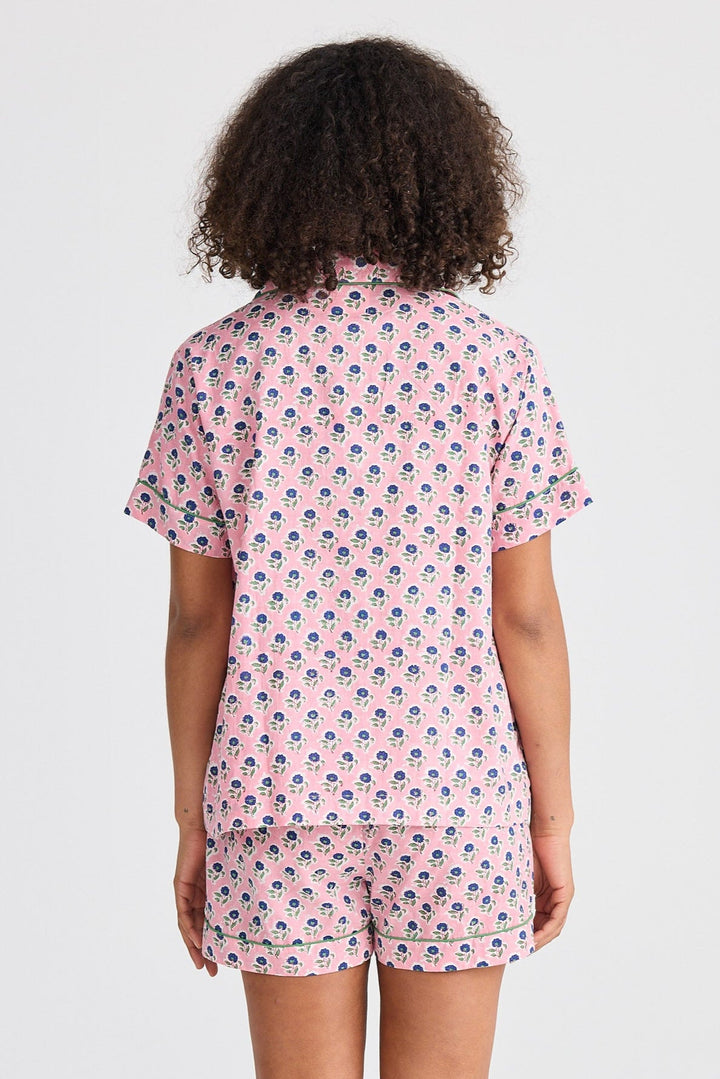 Person wearing a pink patterned pajama set on a white background