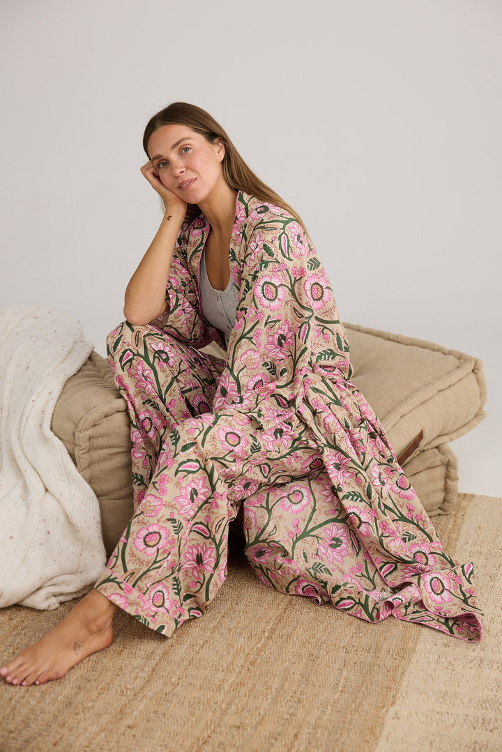 Woman sitting on a couch wearing a pink floral robe.