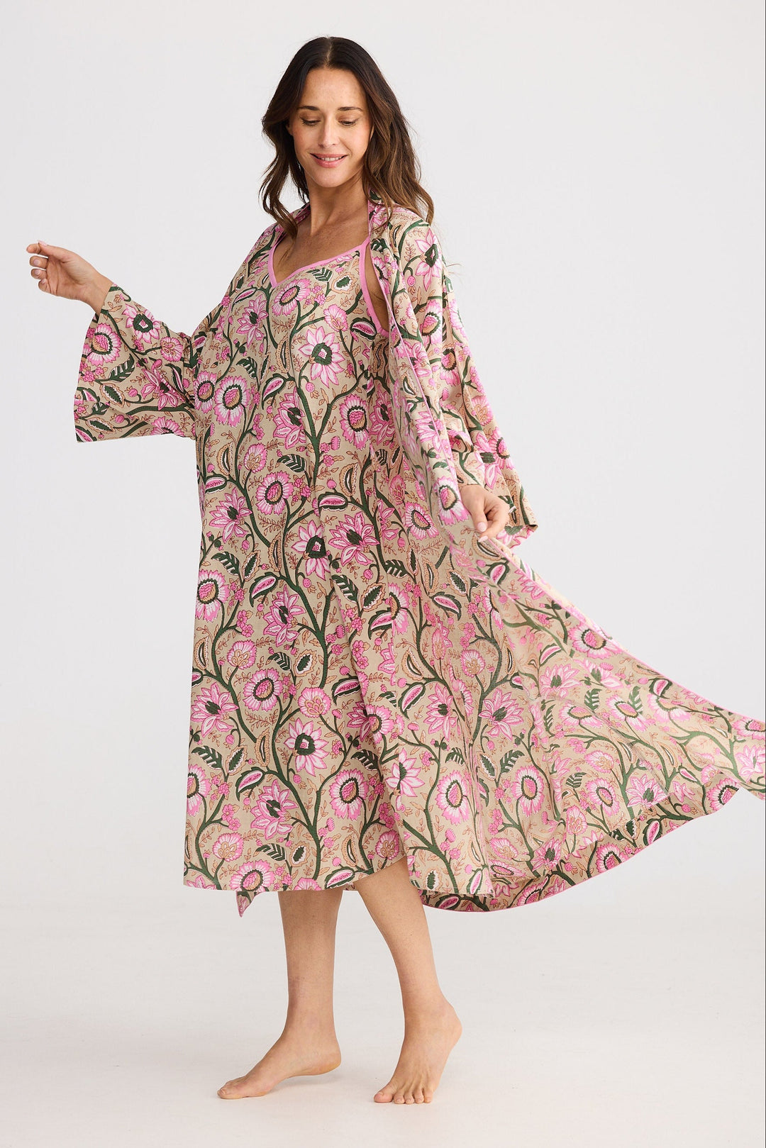 Woman wearing a pink floral dress and robe on a white background