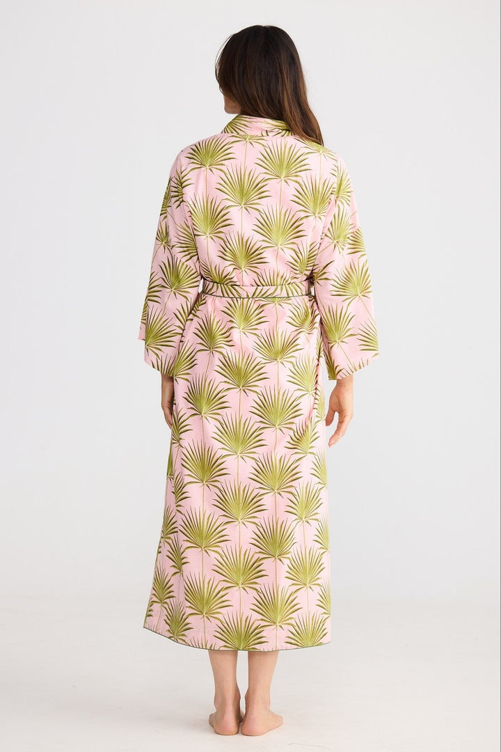 Woman wearing a pink and green patterned robe against a white background