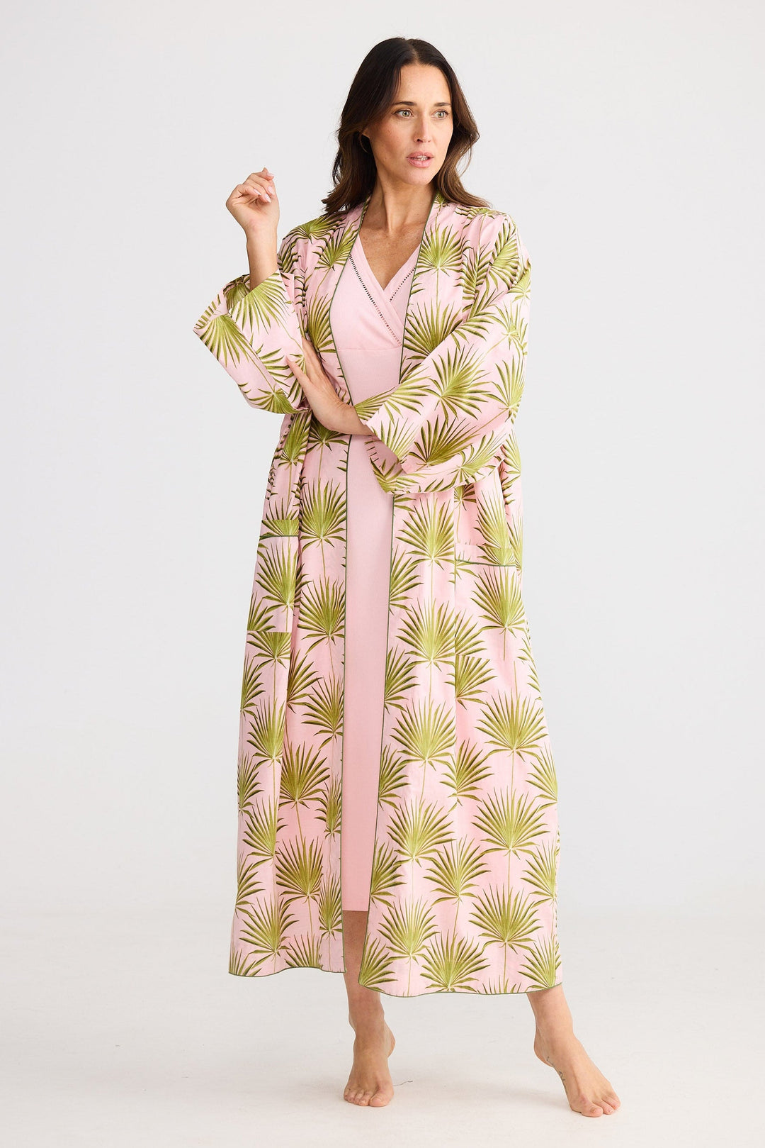 Woman wearing a pink robe with green palm leaf pattern on a white background