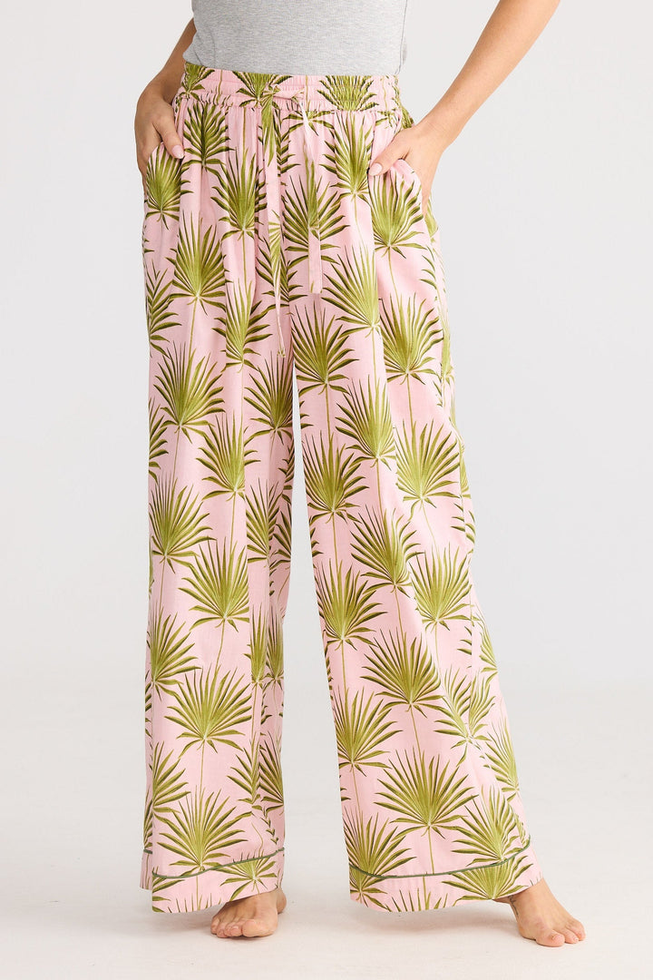 Person wearing pink pants with green leaf pattern on a white background