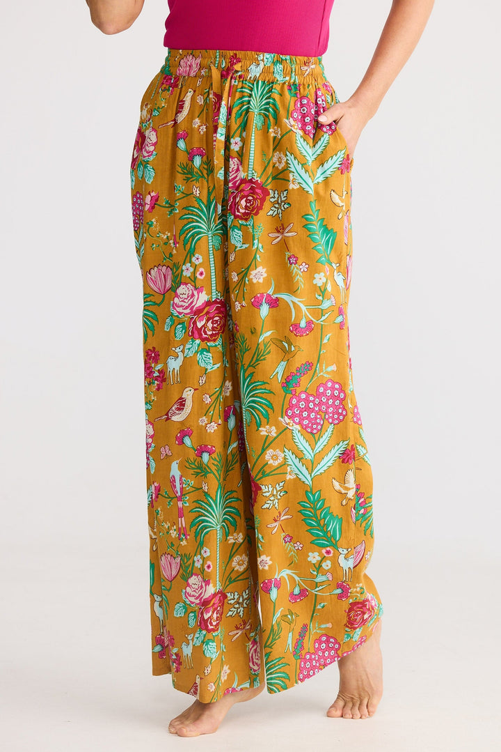 Person wearing mustard yellow floral wide-leg pants on a white background