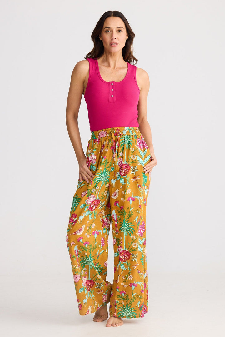 Woman wearing a pink top and yellow floral pants on a white background