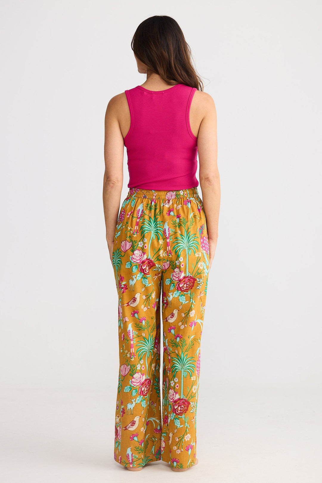 Woman wearing a pink top and colorful floral pants on a white background