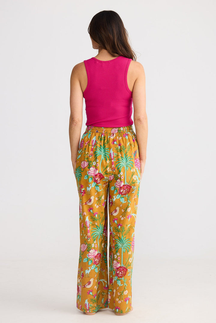 Woman wearing a pink top and colorful floral pants on a white background