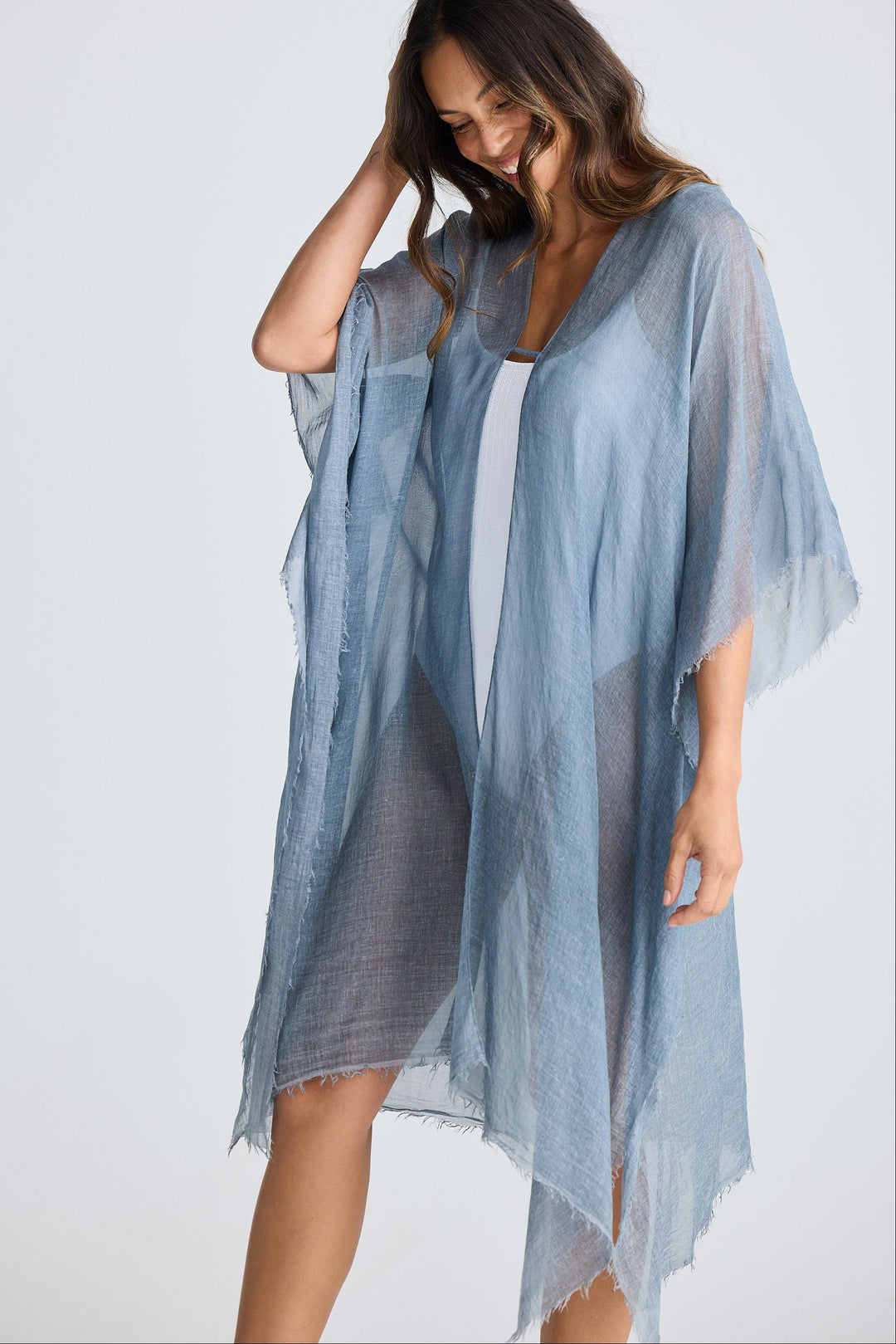 Woman wearing a light blue sheer cover-up against a white background