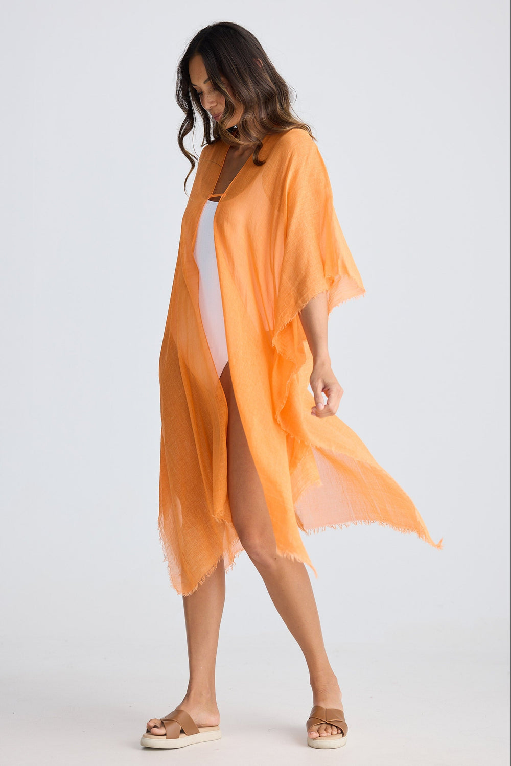 Woman wearing an orange sheer cover-up on a white background