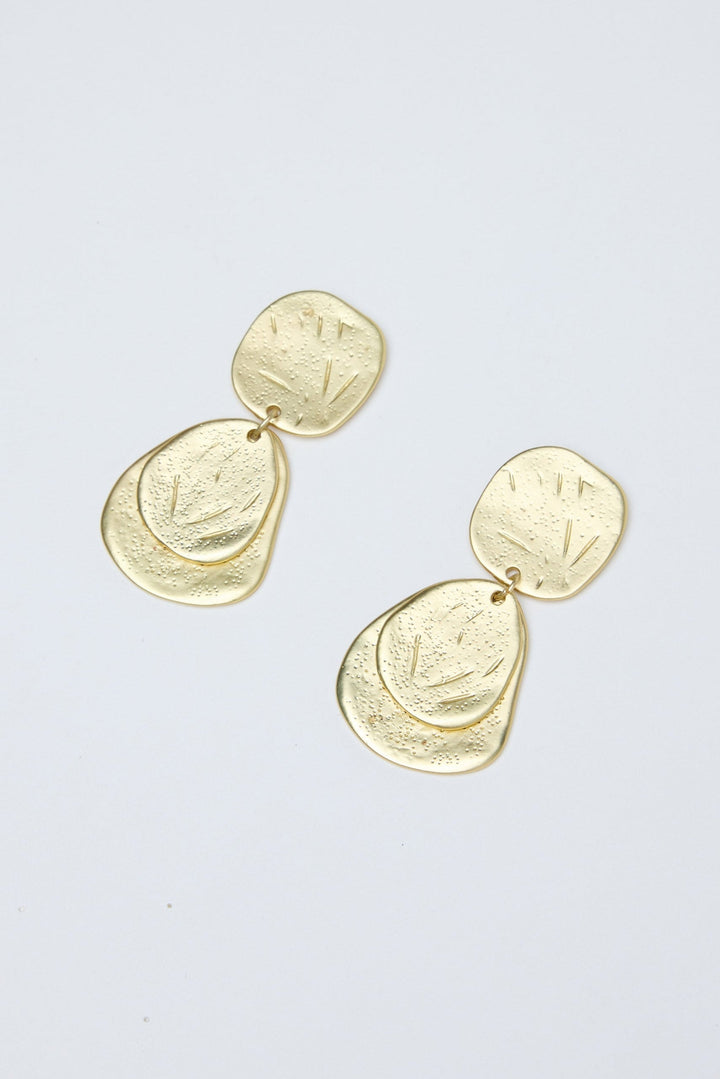Gold earrings on a light gray background
